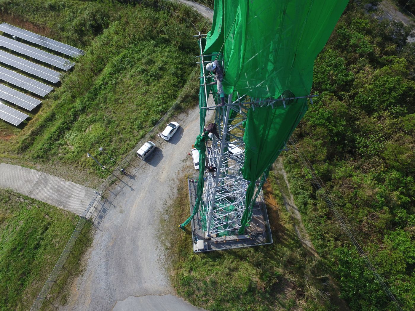 鉄塔基部で作業する職人たちをドローンから見下ろした写真