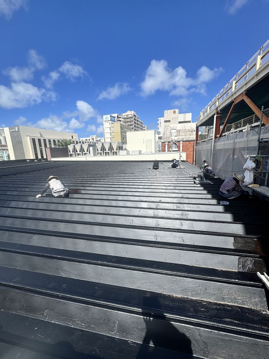 青空の下、塗装作業中の金属屋根