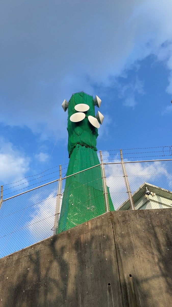 青空を背に、紅白鉄塔の鉄骨に立つ職人